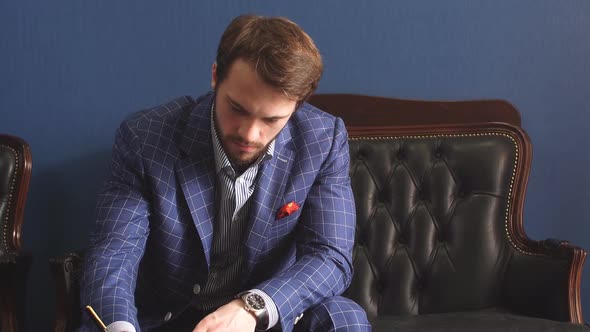 Handsome Young Writer in a Classy Suit Having an Inspiration Mood Making Some Notes , While Sitting