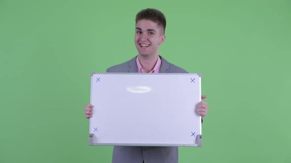 Happy Young Businessman Holding White Board and Looking Surprised