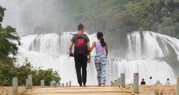 Couple Walking Towards the Majestic Waterfall in the Border of Vietnam and China