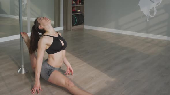 Caucasian woman stretching before pole dancing