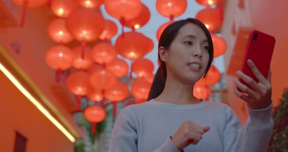 Woman take video on cellphone and speak to the phone with red lantern decoration