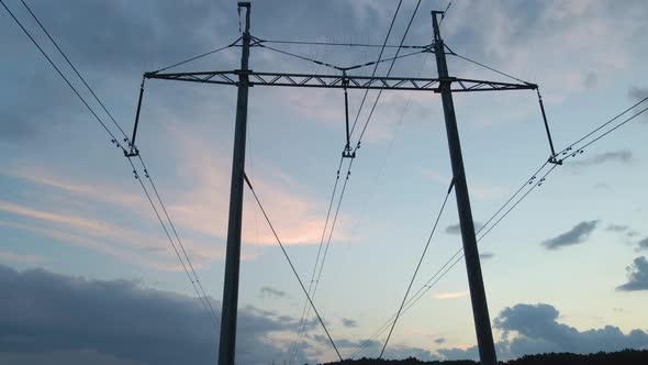 Dark Silhouette of High Voltage Tower with Electric Power Lines at Sunset