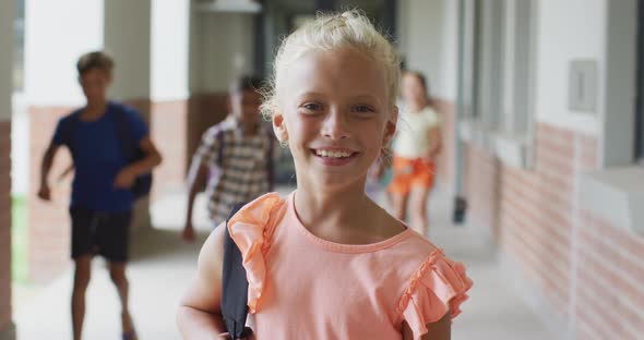 Video of happy caucasian girl standing at school corridor