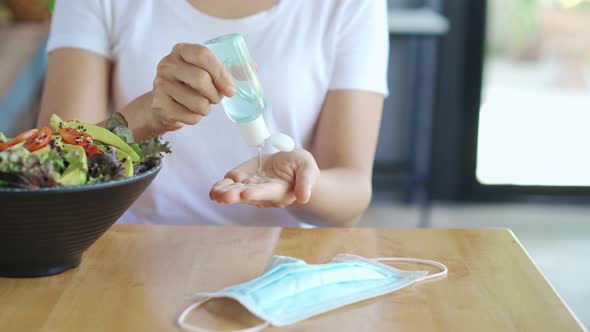 Young woman using alcohol gel sanitizer to avoid infections corona virus and bacteria before meals