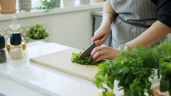 Woman cutting parsley on wooden board