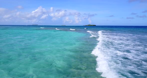 Wide drone island view of a white sandy paradise beach and blue ocean background in vibrant 4K