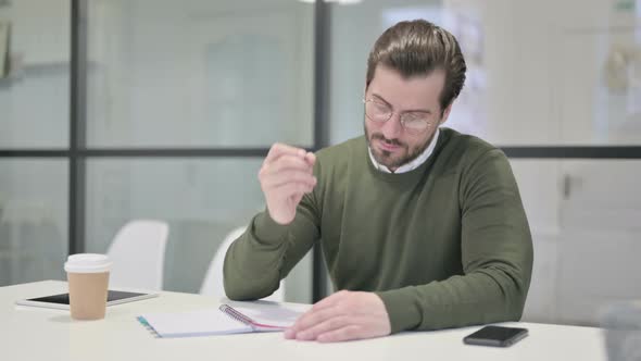 Young Businessman Writing on Paper in Office