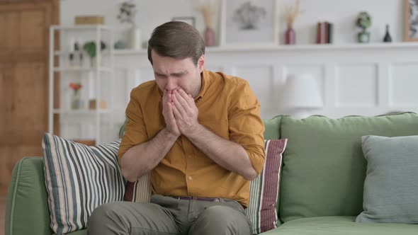 Young Man Coughing while Sitting on Sofa