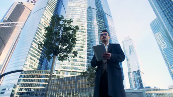 Male Manager Is Walking Along the Business Complex Composed of Skyscrapers