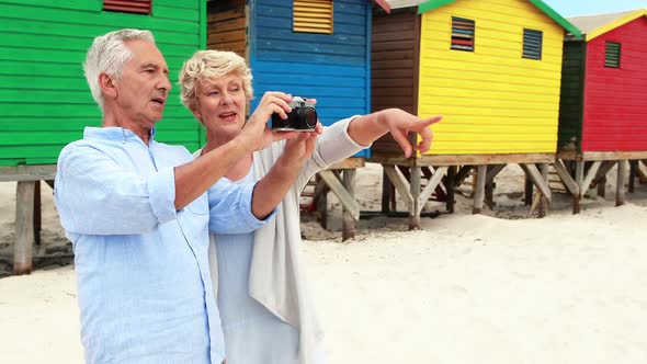 Senior couple clicking photo on camera at the beach