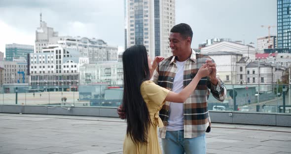 Beautiful Multicultural Loving Couple of Two Cheerful People Dancing at Romantic Date on the Rooftop