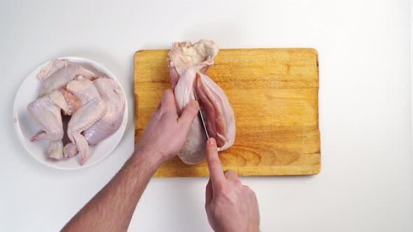 Male Hands Butcher Carcass of Raw Chicken on a Wooden Cutting Board