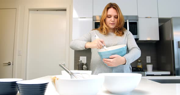 Woman mixing dough in bowl for baking