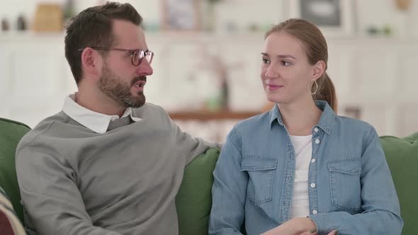 Happy Couple Having Conversation While Sitting on Sofa