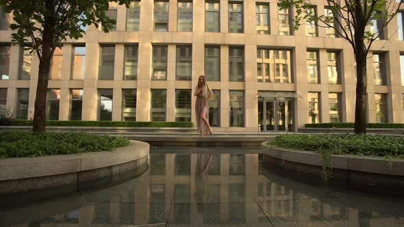 Beautiful Young Girl Dancing on the Street of a Modern City and Is Reflected in the Water. Slow