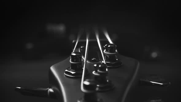 A headstock of a fretless electric bass guitar on the dark background, black and white