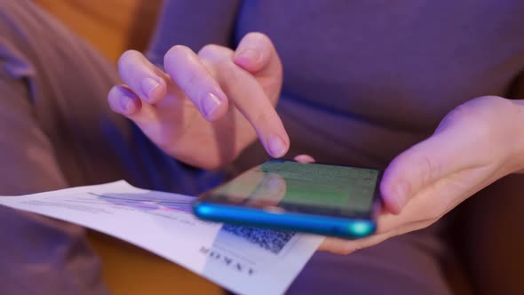 a Woman is Sitting in a Yellow Armchair and Typing on a Smartphone