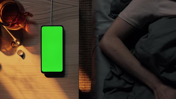 Mobile with Green Screen Charging While Woman Sleep in Bed