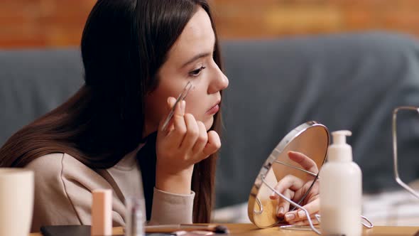 Young Woman Tweezing Her Eyebrows Looking at Mirror with Tweezers at Home Slow Motion