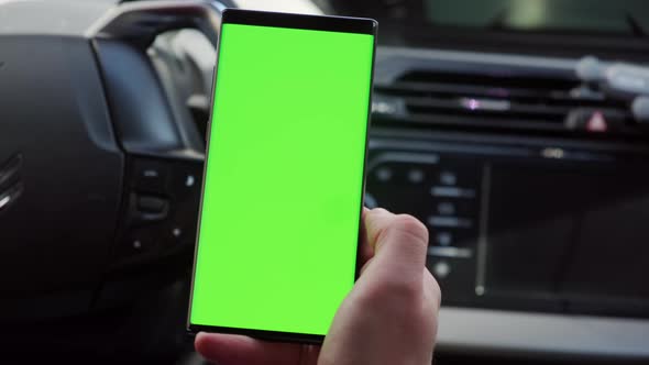 Close Up Hand of the Driver in Car Uses a Smartphone with a Green Screen Inside a Car