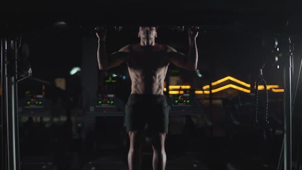 Athletic Man Performs Pullups on the Horizontal Bar Strength Training in the Gym Cinematic Light