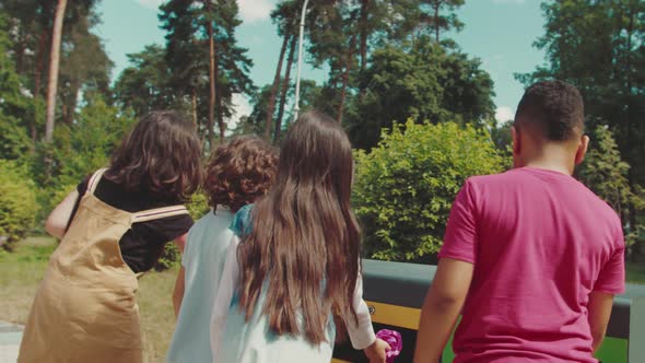 Group of Multiethnic Kids Throwing Garbage in Recycle Dustbin Outdoors