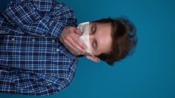 Teenager Coughs in a Mask on a Blue Background