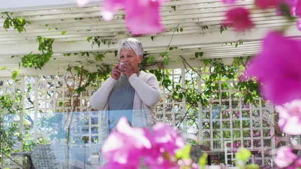 Senior mixed race woman drinking coffee on balcony in garden