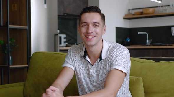 Portrait of Happy Man Is Resting While Sitting on Couch at Home. A Young Male Enjoys the Lifestyle