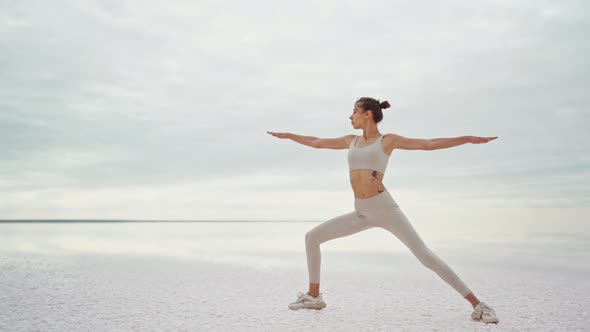 Fitness Woman Practicing Asana Yoga Pose on Salt Beach at Dramatic Sunrise Sky