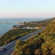 The camera flies over cars driving along a winding road amongst the mountains and the seashore - VideoHive Item for Sale