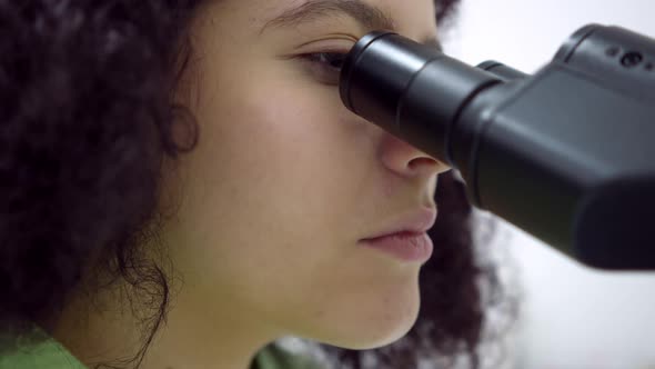 Closeup Face of Concentrated Scientist Using Microscope in Laboratory Indoors