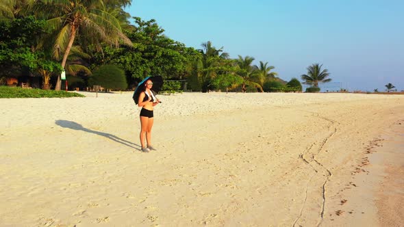 Female models happy and smiling on paradise tourist beach vacation by aqua blue ocean and bright san