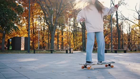 Side View of a Teenage Girl Quickly Rides Along the Sidewalk in Sunny Weather