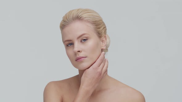 Studio portrait of young, beautiful and natural blond woman applying skin care cream. F