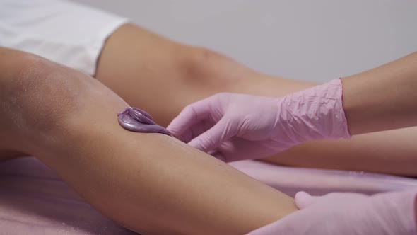 Cosmetologist Placing Paste on Woman's Leg in Beauty Salon