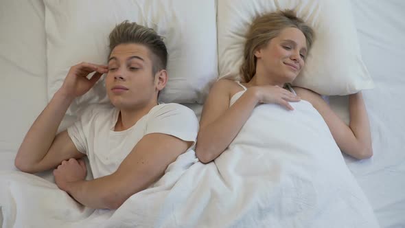 Teenagers Waking Up Together in Bed, Smiling and Holding Hands, First Love