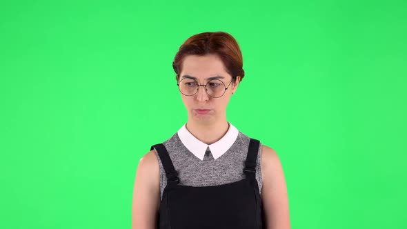 Portrait of Funny Girl in Round Glasses Is Very Offended and Looking Away. Green Screen