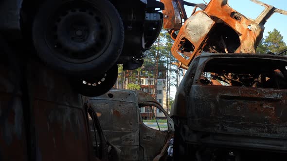 Zoom Out of Car Dump with Burnt Down Automobiles in Ukraine and Modern Building at Background