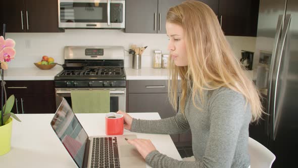 Attractive woman working from home while sitting in her kitchen