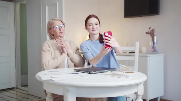 The Girl Takes a Selfie on the Phone with Her Grandmother