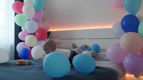 Cute Small Child Playing on Bed in Bedroom Decorated with Colorful Balloons 1 Year Old Baby Boy