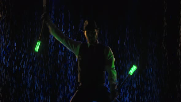 A Light Fire Show Performed By a Stylish Man Against a Background of Water Droplets Illuminated