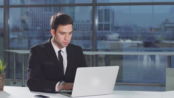 Serious Handsome Man Working Using Laptop Looking in Monitor Screen