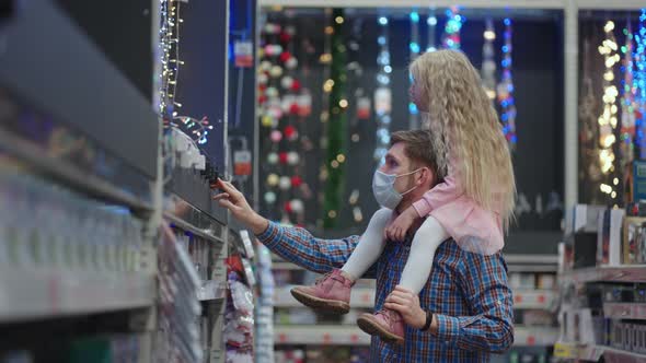 Father and Daughter on Shoulders Choose Christmas Garlands for Christmas in the Supermarket