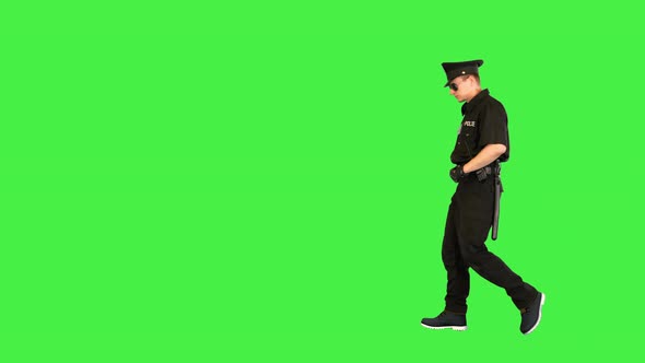 Policeman in Uniform Walks Looking Around on a Green Screen Chroma Key