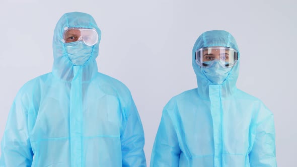 Medical Workers, Doctor and Nurse, in Special Protective Uniforms, Masks, Goggles, Looking at Camera