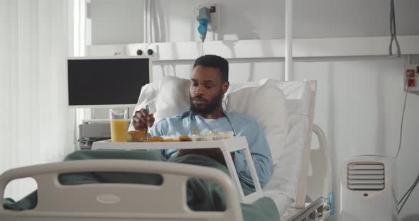 African Male Patient Enjoying Meal in Hospital Bed