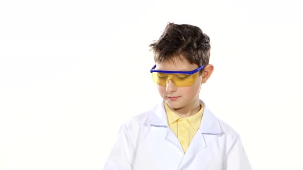Scientist Boy in Uniform and Protective Glasses with Test Tubes, Evaluates, Isolated on White