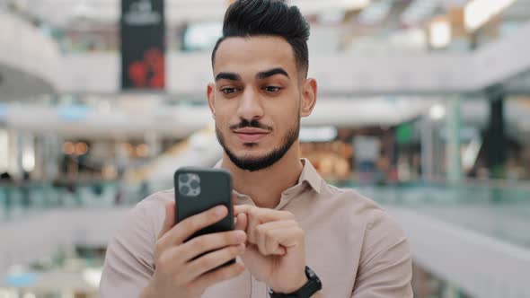 Happy Smiling Young Arab Male Holding Phone Amazed Joyful Guy Get Cash Prize Lottery Winner Hispanic